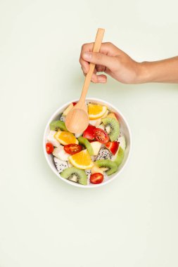 Beyaz arka planda bir kase sağlıklı taze meyve salatası. Üst görünüm.