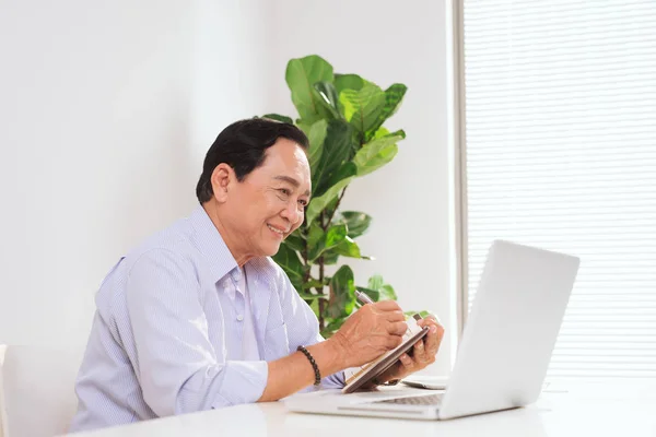 Senior man working with laptop and basic things for work at his desk