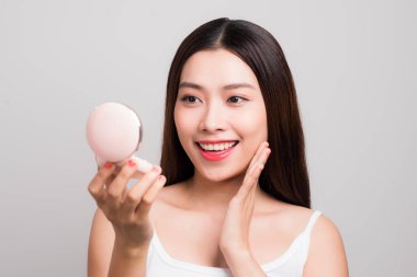 Güzel genç Asyalı kadın ile mükemmel taze temiz ten aynaya bakıyor.