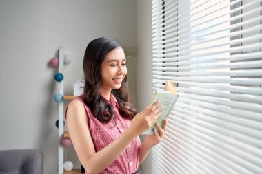 Genç kadın evde pencere oturma odası okuma kitabında rahatlatıcı yakın duran.