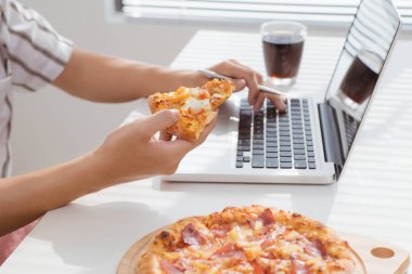 Erkek el dizüstü bilgisayarda çalışarak pizza yemek kadar kapatın