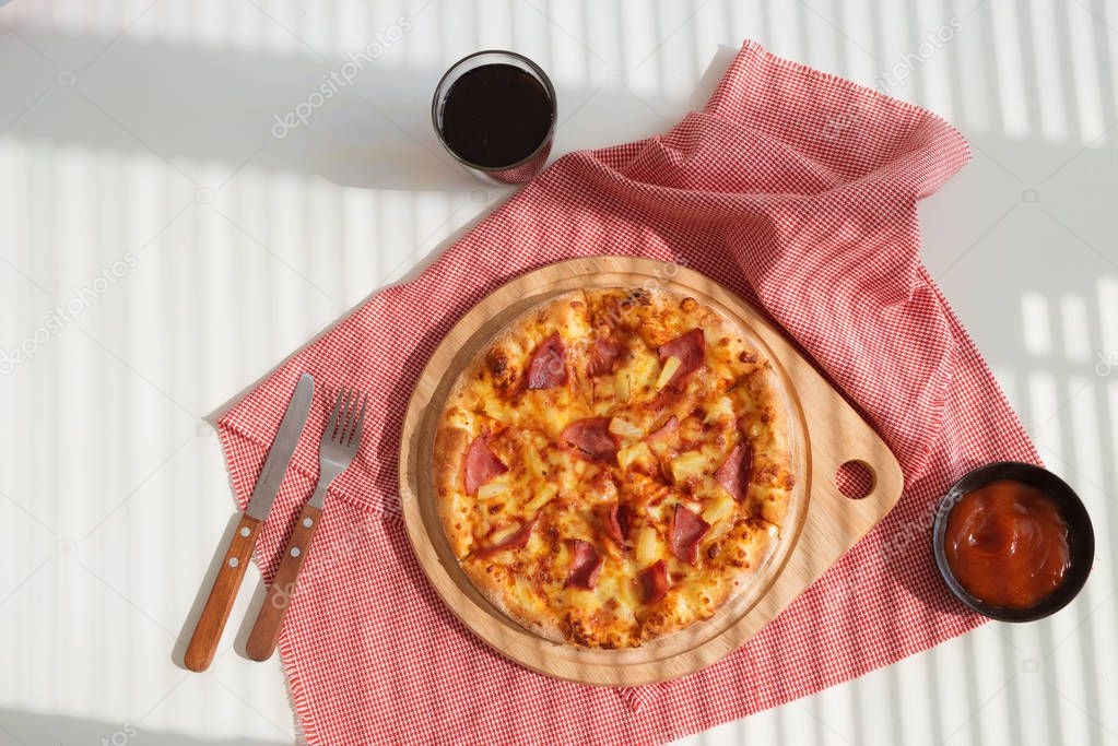 Delicious fresh pizza served with sauce and soda glass on white table with pink napkin, top view