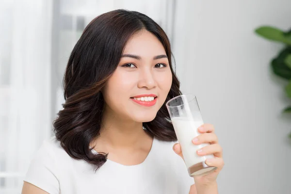 Healthy woman is drinking milk from a glass isolated on white background.
