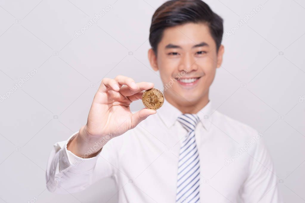 young business man holding a bitcoin gold coin
