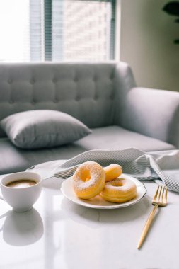 Klasik çörek ve kahve ile arka koltukta beyaz masada Kupası.