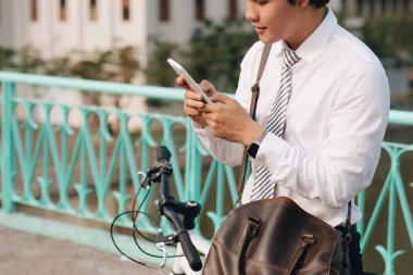 Bisikletli genç adam cep telefonuna bakıyor..