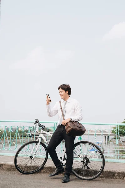 young urban fashion man with bike and mobile phone