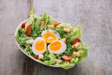 Yüksek açılı görünüş ile haşlanmış yumurta dilimleri, besleyici bir sebze salatası hizmet bir ahşap masa üstünde beyaz bir plaka üzerinde