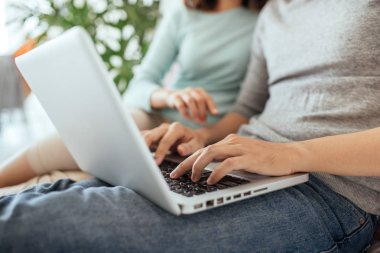 Evde internet tarama, dizüstü bilgisayar kullanarak ve gülümseyen genç Asyalı Çift