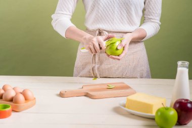 Ev kadını önlük yapımı giyiyor. Yemek elma pasta yapma adımları. Yeşil elma soyma.