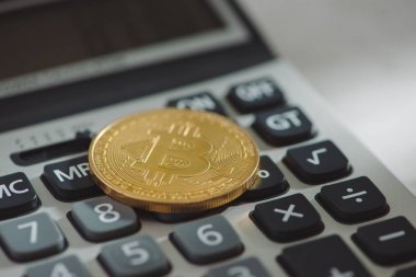 Beyaz arka plan üzerinde hesap makinesiyle altın bitcoin