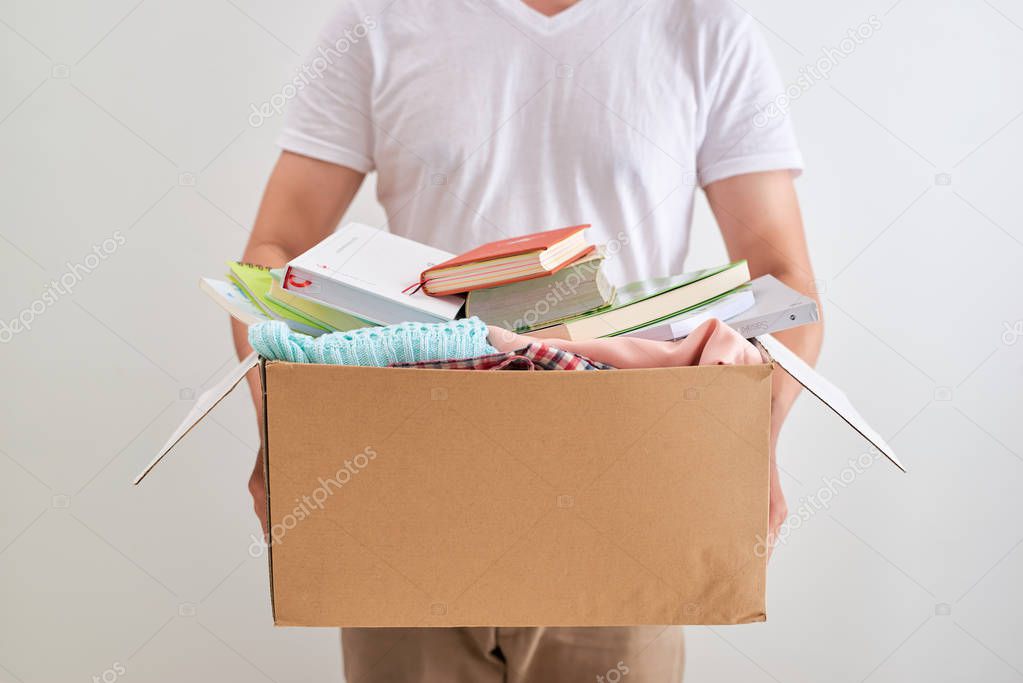 Man holding donate box with books and clothes. Donation concept.