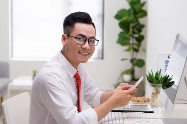 Ofiste cama tabloda, bilgisayar ve akıllı telefon kullanan adam