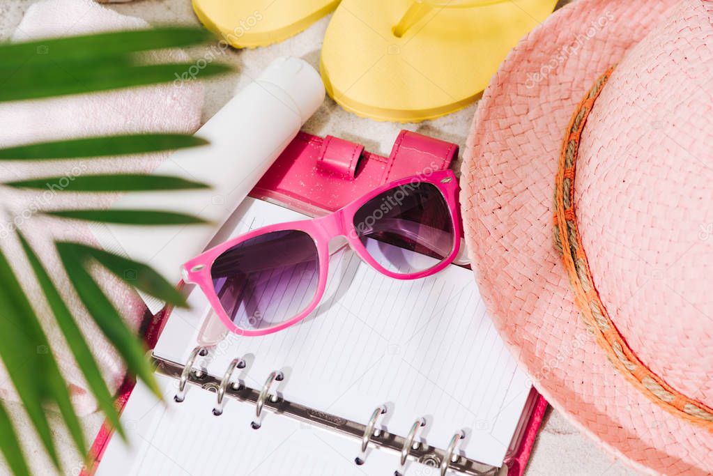 Colorful summer beachwear, flip flops, towel, hat, sunglasses and book on sand beach.