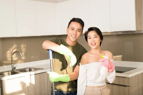 Housewife and her husband cleaning home and having fun together. Housekeeping, home cleaning and cleaning service concept