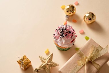 Noel kartı. Açık sarı arka planda hediye kutuları, süslemeleri ve şekerlemeleri olan kek. Tatiller.