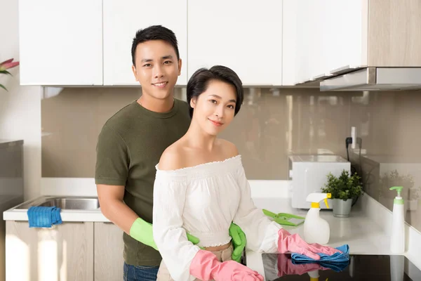 Young happy Asian couple is having fun while doing cleaning at home.