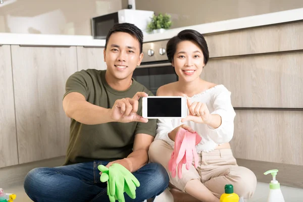 Pareja Joven Haciendo Tareas Domésticas Mientras Muestra Teléfono Móvil Cocina — Foto de Stock