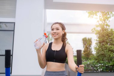 Sunny Park 'taki spor salonunda egzersiz yaptıktan sonra maden suyu içen kadın sağlıklı, sportif yaşam tarzları ve zayıflama.
