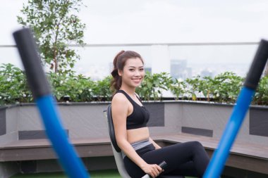 Parktaki makineler üzerinde egzersiz yapan bir kız.