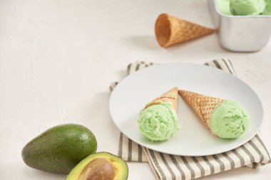 Yeşil avokado dondurma kaşık toz beyaz arka plan üzerinde wafle koni içinde. Kopya alanı