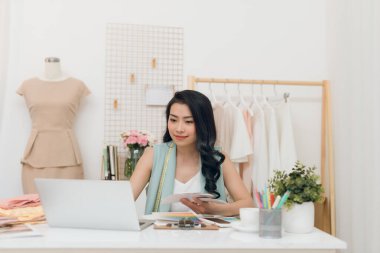 Atölyede bilgisayar kullanarak Güzel genç Asya iş kadını / moda tasarımcısı