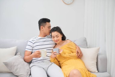 Sevecen bir çift kahve fincanları tutarak koltukta oturuyor.