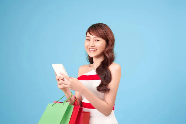 아름다운 여성은 파란색 스튜디오에서 온라인 쇼핑을위해 스마트 사용하고 있습니다 — 스톡 사진