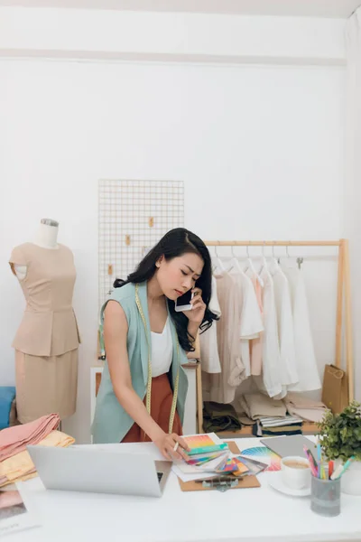 Beautiful Female Fashion Designer Using Laptop Cell Phone Studio — стоковое фото