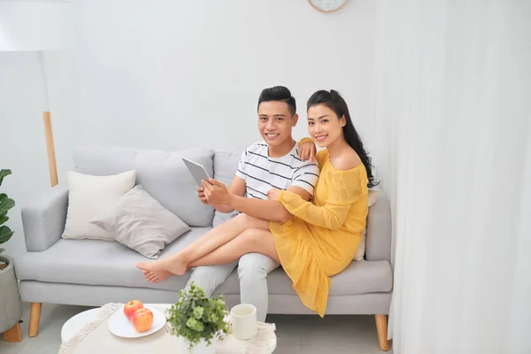 Jovem casal assistindo conteúdo de mídia on-line em um tablet sentado o — Fotografia de Stock