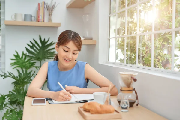Souriant Jeune Entrepreneure Asiatique Assise Une Table Écrivant Des Notes — Photo