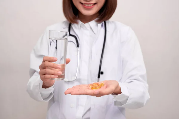 医生妇女拿着水和药物在白色背景 — 图库照片