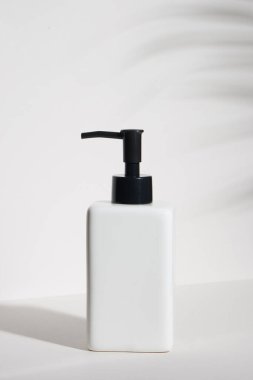 Beyaz arka planda izole edilmiş tropikal yapraklı boş bir kozmetik şişe.