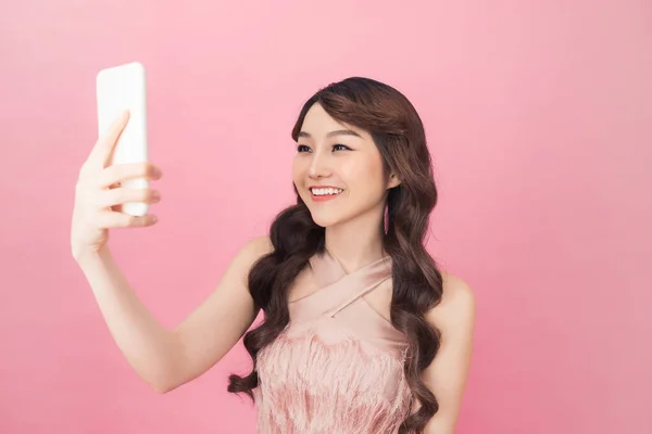 一个美丽的年轻亚洲妇女穿着粉红色的礼服摆姿势 而站在和采取自拍 — 图库照片