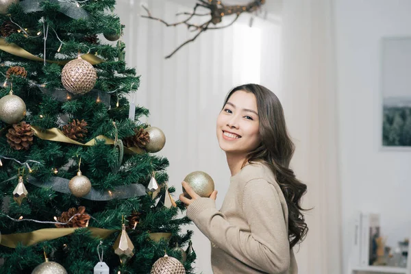 Asyalı Kadın Noel Ağacına Altın Noel Topu Asıyor — Stok fotoğraf