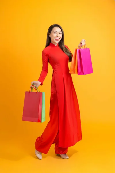 Азиатка Красном Платье Дай Держа Сумки Изолированы Желтом Фоне Счастливого — стоковое фото