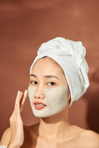 一位漂亮的年轻亚洲姑娘头上戴着一条白毛巾 戴着一副有用的粘土面罩 — 图库照片