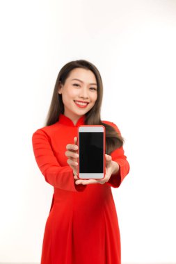Aao dai 'deki genç Asyalı kadın beyaz arka planda boş akıllı telefon ekranı gösteriyor.