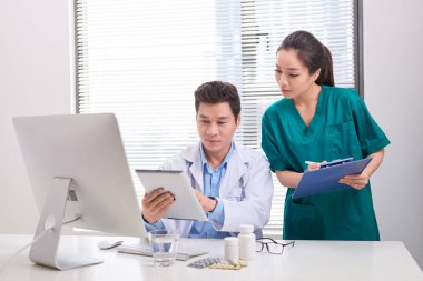 Bir grup doktor ve hemşire hastanın tıbbi raporunu inceliyor. Hastanede hasta dosyası üzerinde birlikte çalışan doktorlardan oluşan ekip.