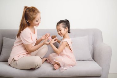 Onu daha mutlu ve daha güzel yapmak için anne pembe oje şirin kızının çivi boya kullanarak