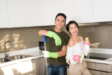 Genç mutlu Asyalı çift evde temizlik yaparken eğleniyor..