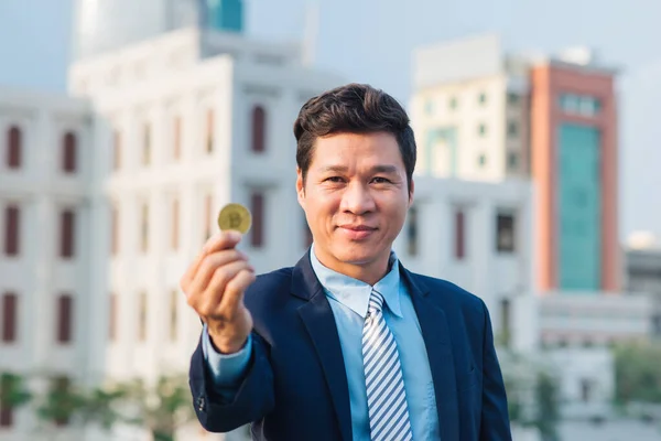 Golden bitcoin in hand of business man with black suit