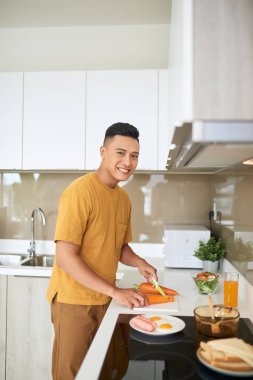 mutlu genç adam mutfakta sebze kesme