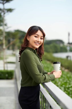 Parkta sıcak içecekten hoşlanan güzel bir kadın