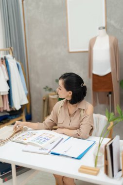 Atölyesinde çalışan genç bir moda tasarımcısı.