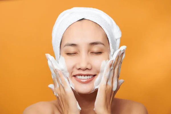 Happy Young Asian Woman Applying Face Cream While Wearing Towel — 图库照片