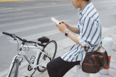 Bisiklet park ile otururken telefon kullanan genç adam