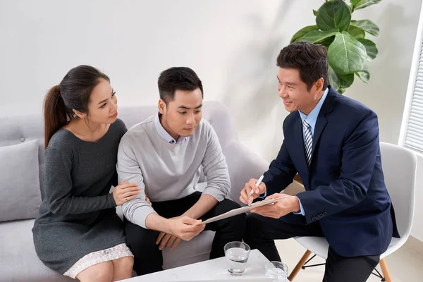 Försäljningskonsult Som Visar Nya Investeringsplaner För Unga Asiatiska Par — Stockfoto