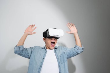 Genç mutlu ve heyecanlı Asyalı adam sanal gerçeklik VR 360 görüş gözlüğü takıyor ve video oyununun tadını çıkarıyor. 
