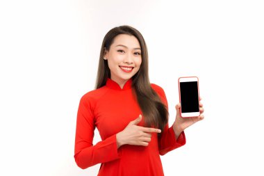Kırmızılı güzel Vietnamlı kadın beyaz üzerine izole edilmiş bir akıllı telefon görüntüsü sergiliyor.